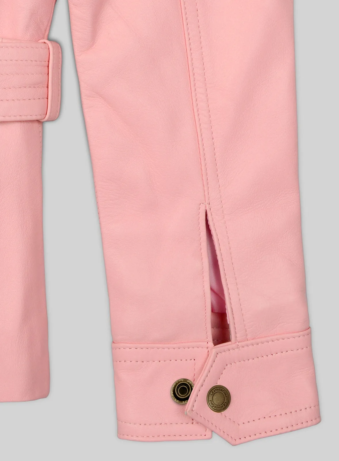 Detail of light pink leather jacket sleeve cuff with brass snap and vent