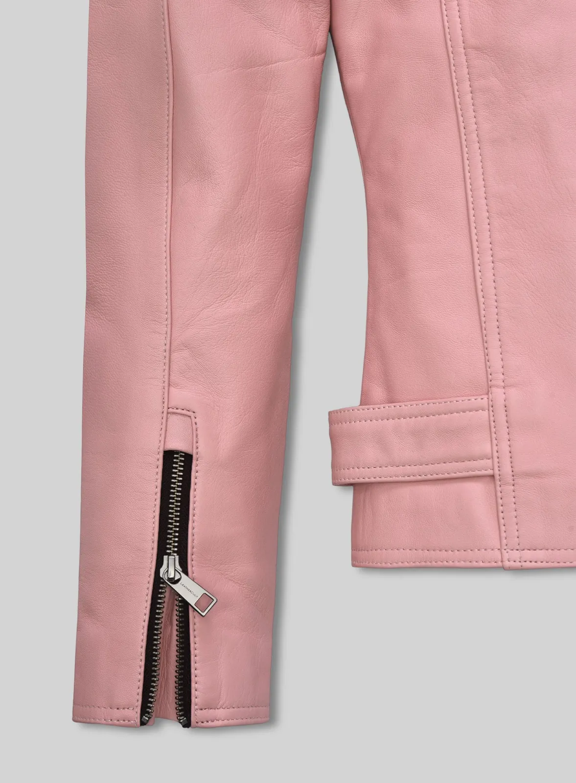 Close-up of zippered sleeve cuff and waist tab on a light pink leather jacket