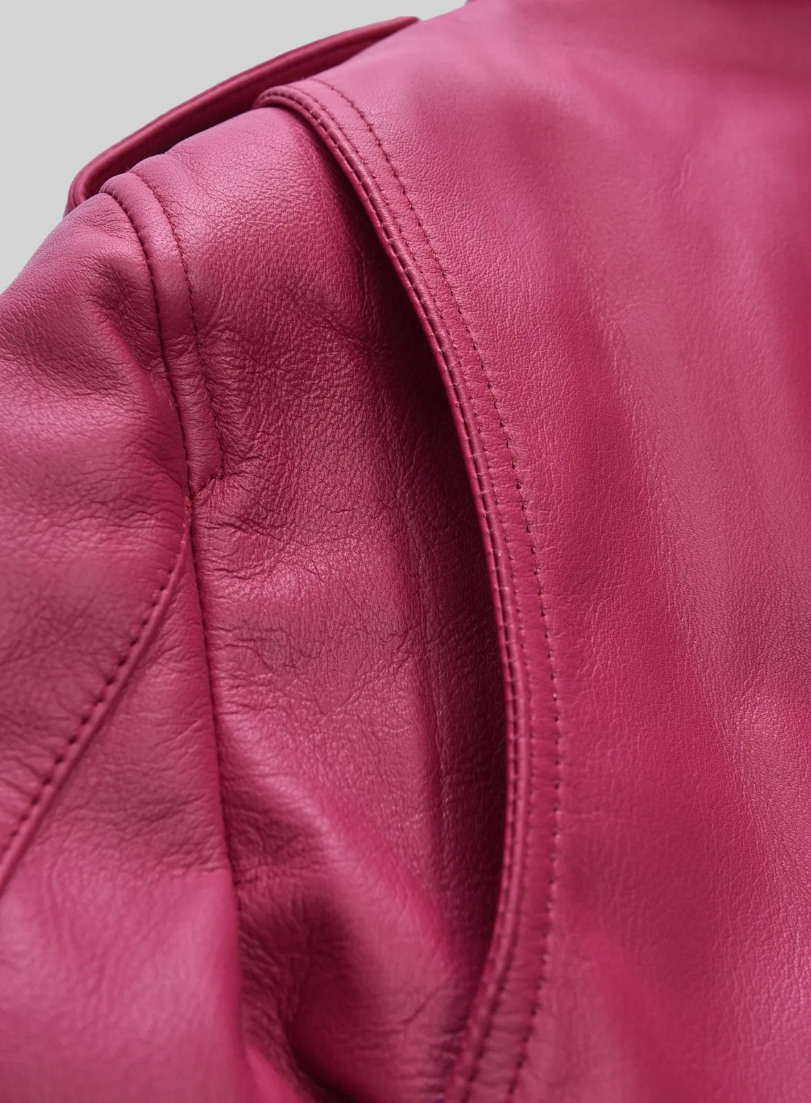 Close-up of pink leather jacket shoulder with stitched seam and epaulette