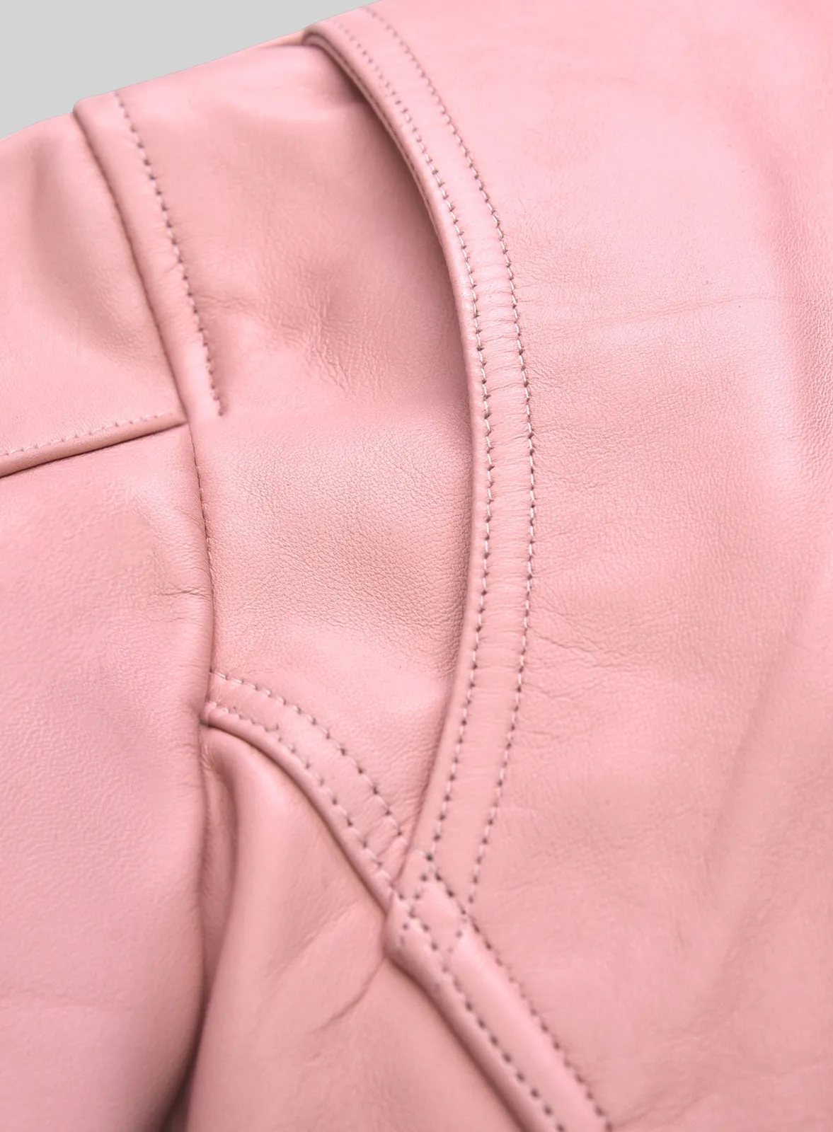 Close-up of shoulder seam and stitching on a light pink leather jacket